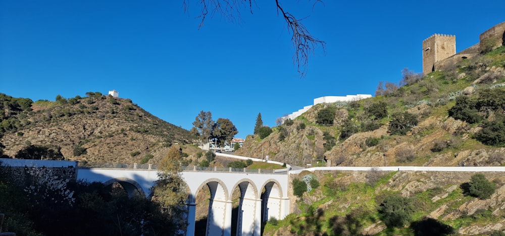 a bridge over a river next to a lush green hillside