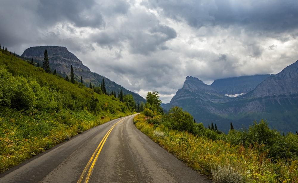 a road with mountains in the background under a cloudy sky
