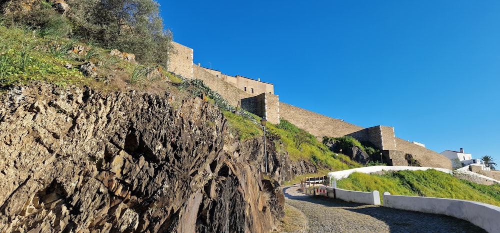 a large stone wall next to a lush green hillside