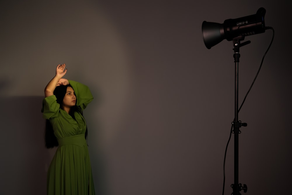 a woman in a green dress standing in front of a camera