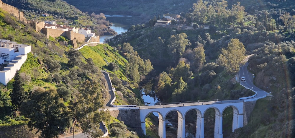 a bridge over a river next to a lush green hillside