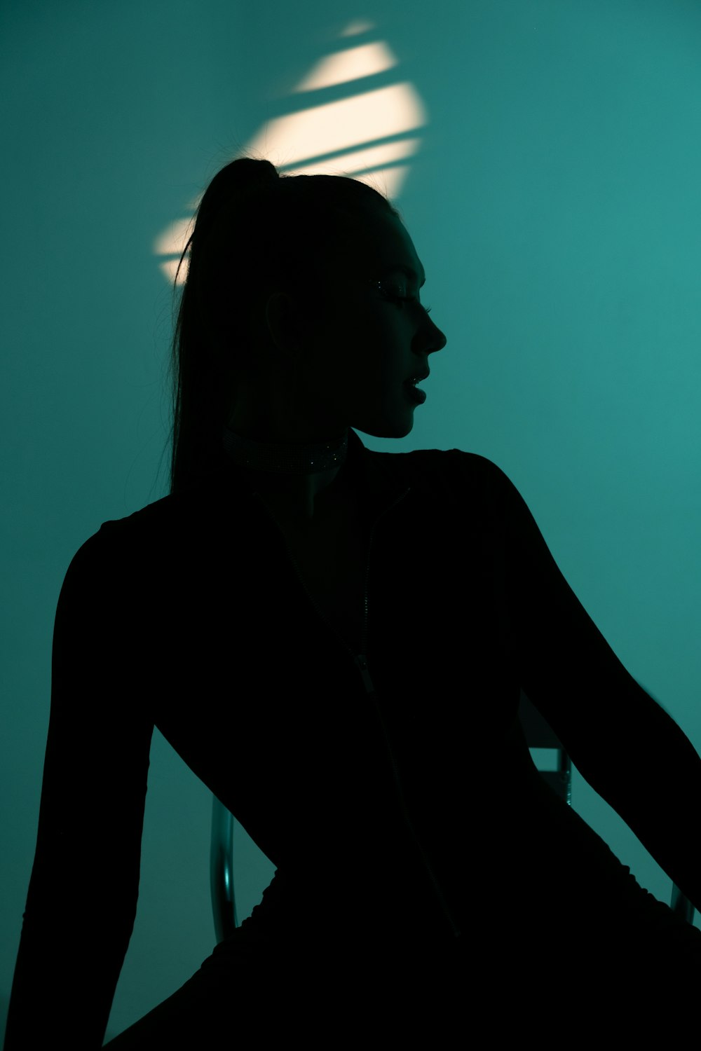 a woman sitting in a chair with her shadow on the wall