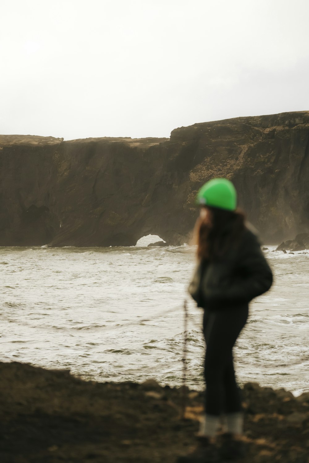 a woman with a green hat standing by the water