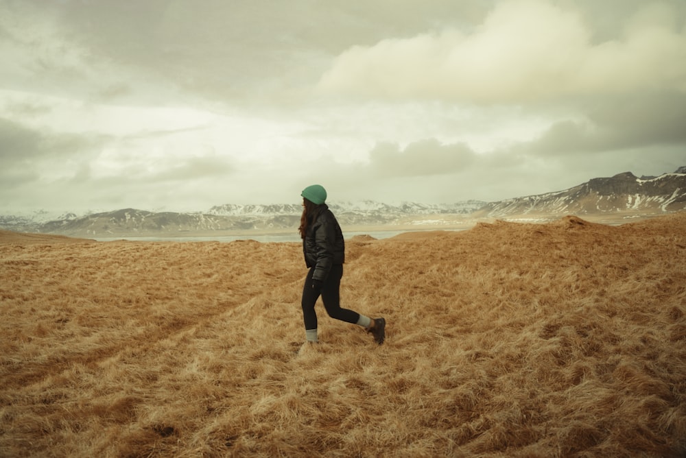 a person running through a field with mountains in the background