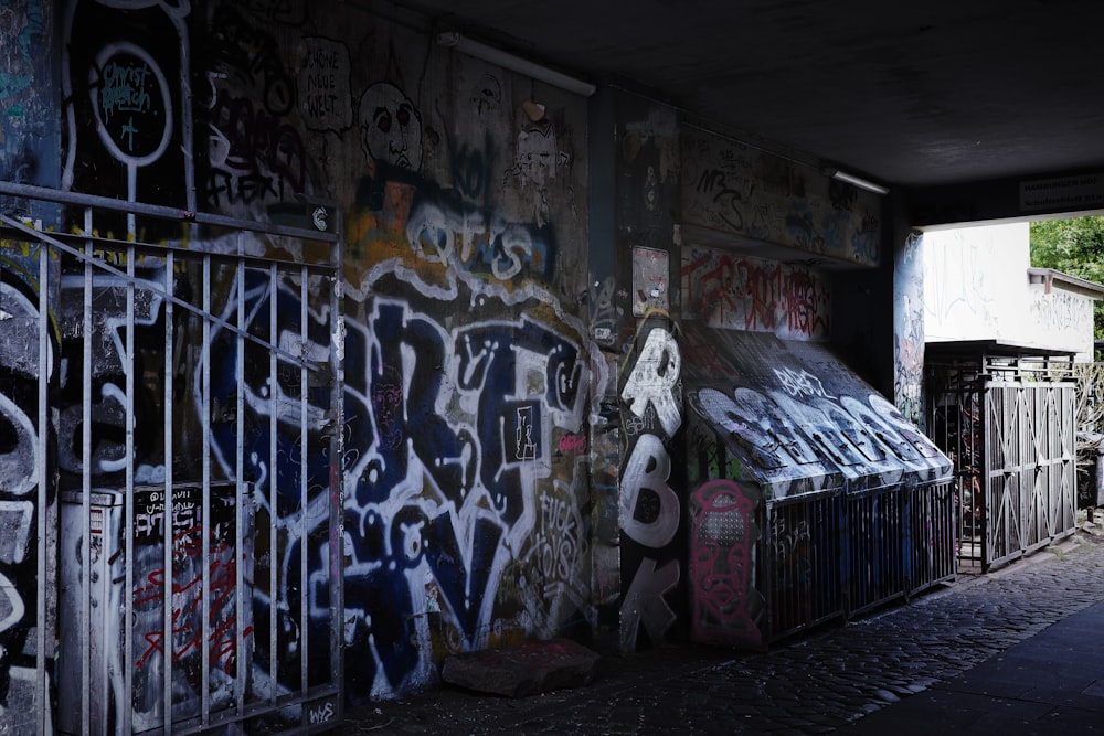 a wall covered in graffiti next to a fence