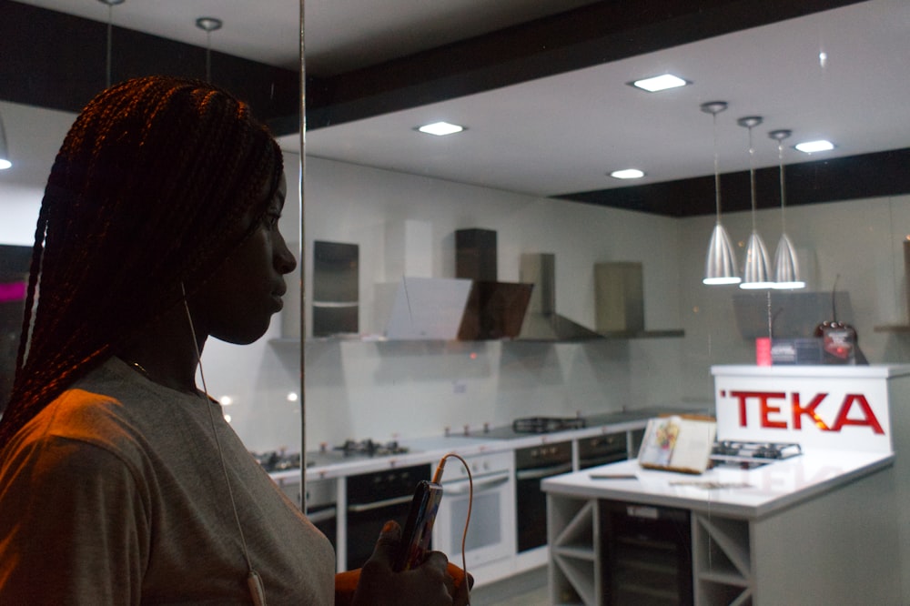 a woman standing in a kitchen looking at her cell phone