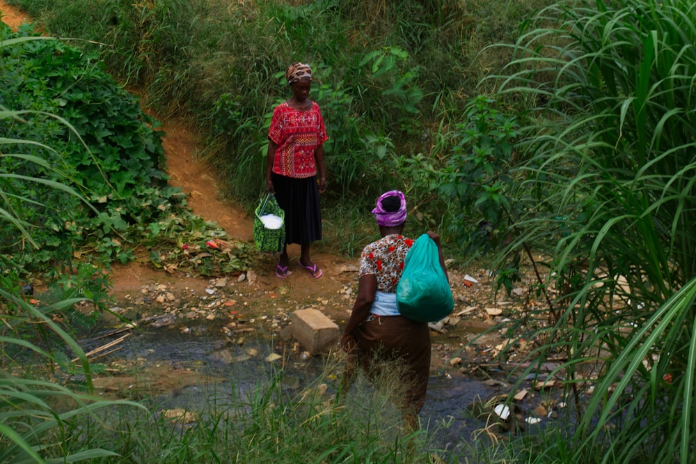 a couple of women walking down a dirt road