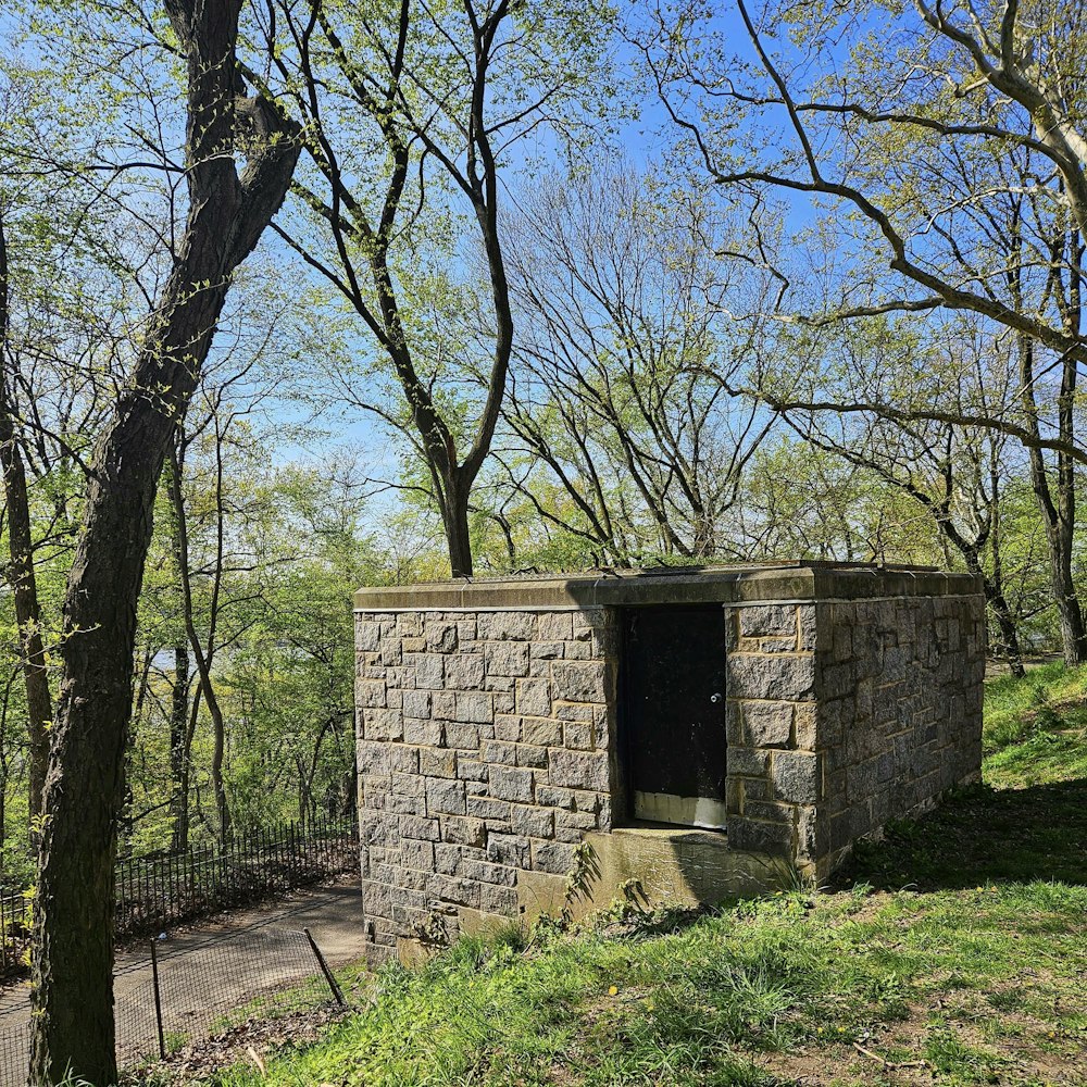 a stone outhouse in the middle of a wooded area
