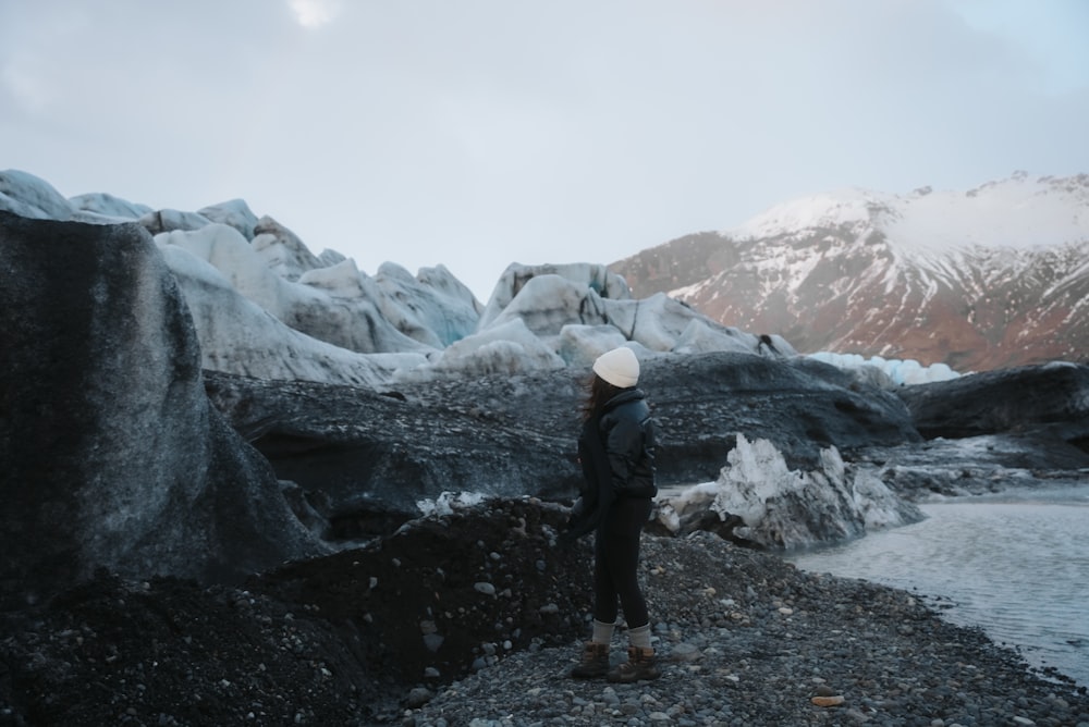 a person standing on a rocky beach next to a body of water