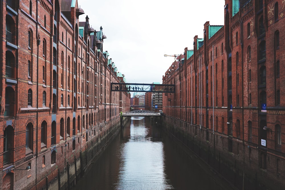 a river running between two brick buildings next to a bridge
