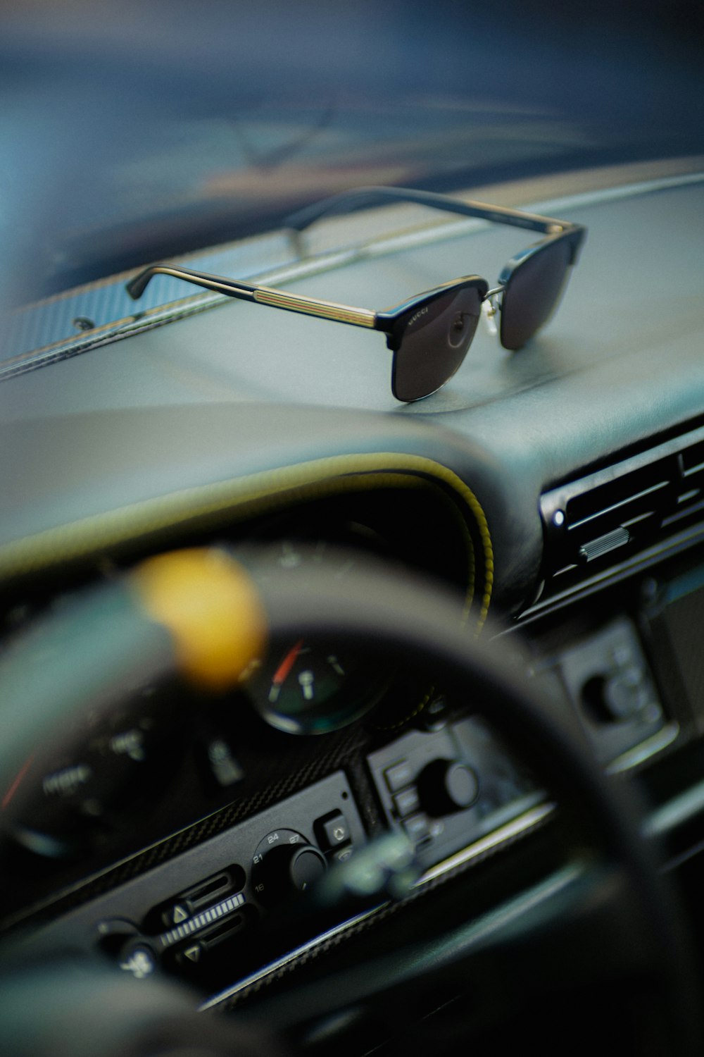 a car dashboard with a steering wheel and a pair of sunglasses