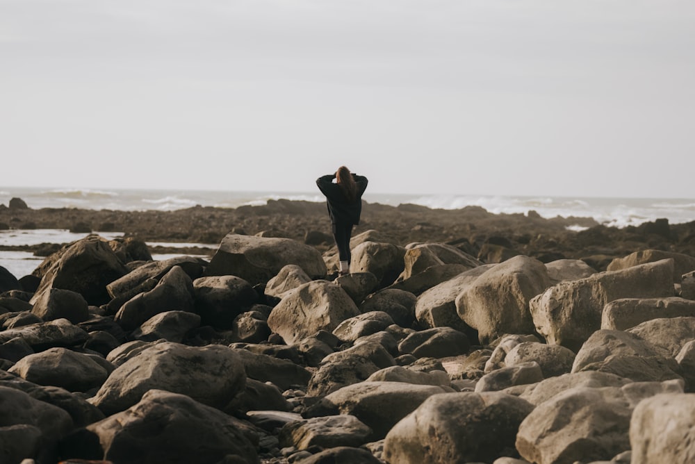 a man standing on a rocky beach next to the ocean