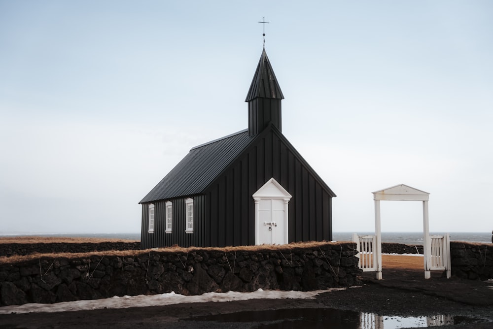 una pequeña iglesia negra con una puerta blanca