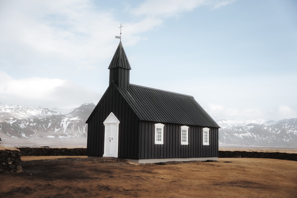 a small black church with a steeple and a cross on top