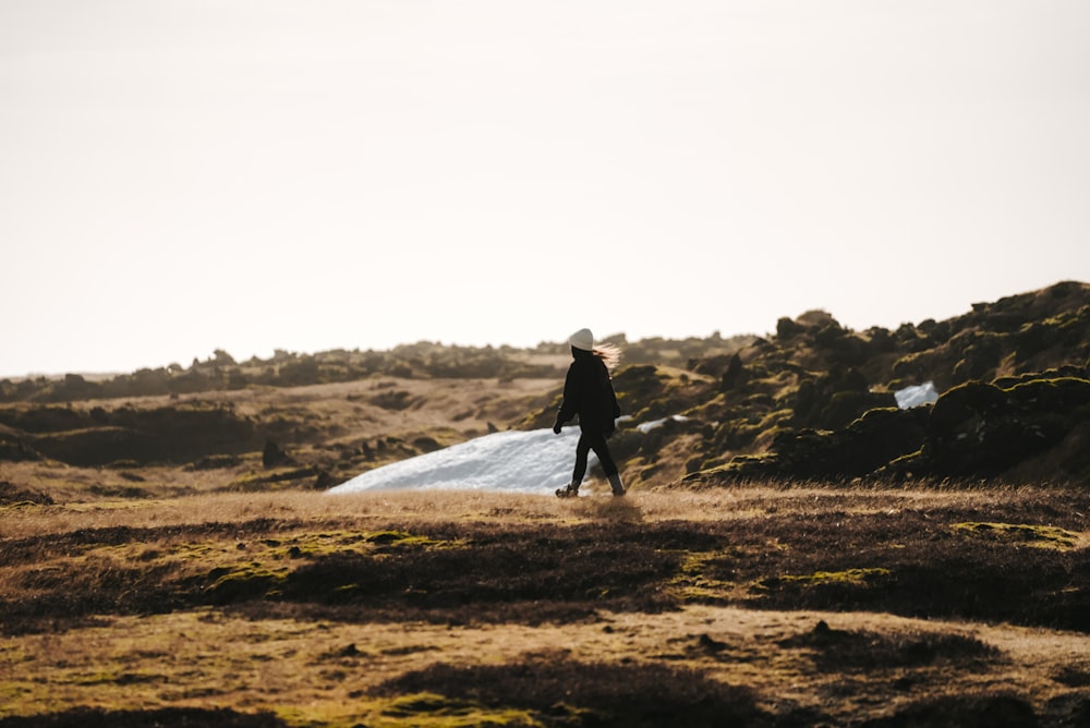 a man walking across a grass covered field