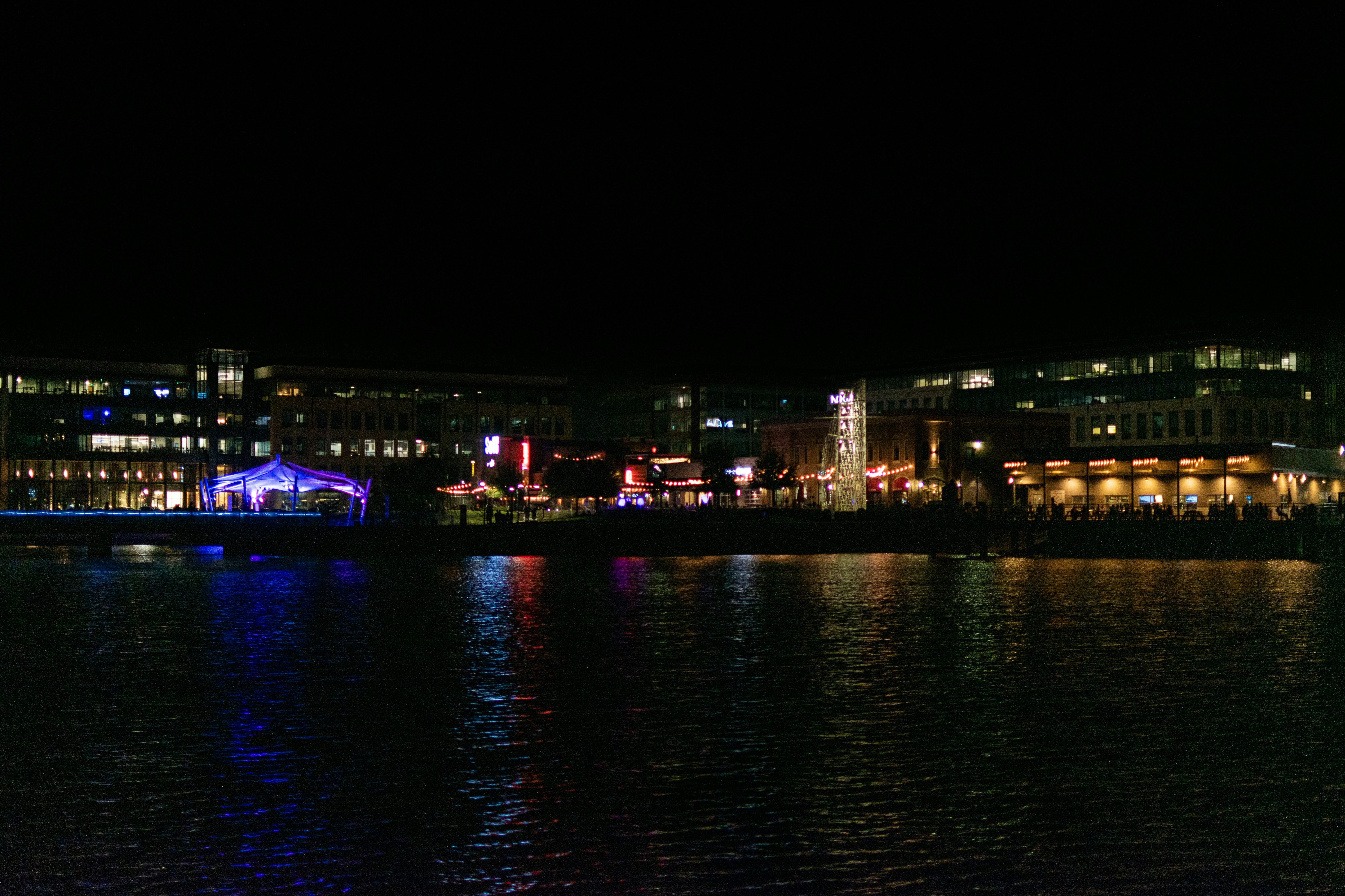 a large body of water at night with buildings in the background