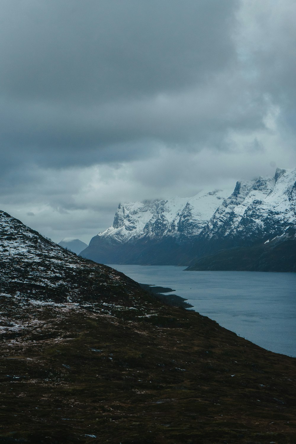 a snow covered mountain with a body of water in the foreground