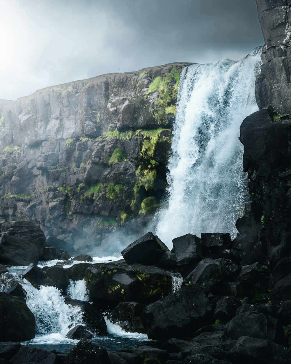 a large waterfall with a man standing on top of it