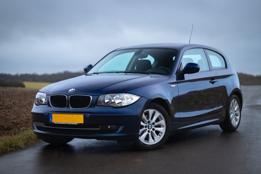 a blue car driving down a wet road