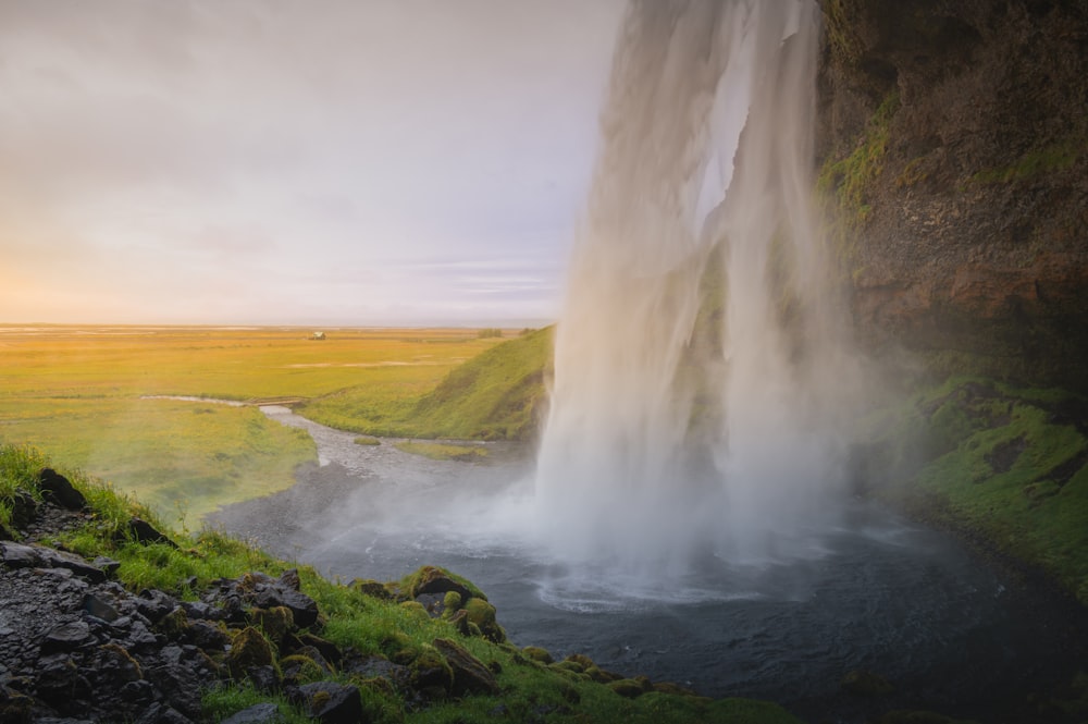 a waterfall in the middle of a grassy field