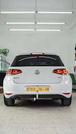 the back end of a white car in a garage
