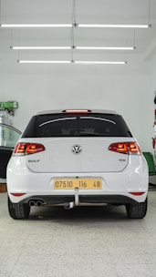 the back end of a white car in a garage