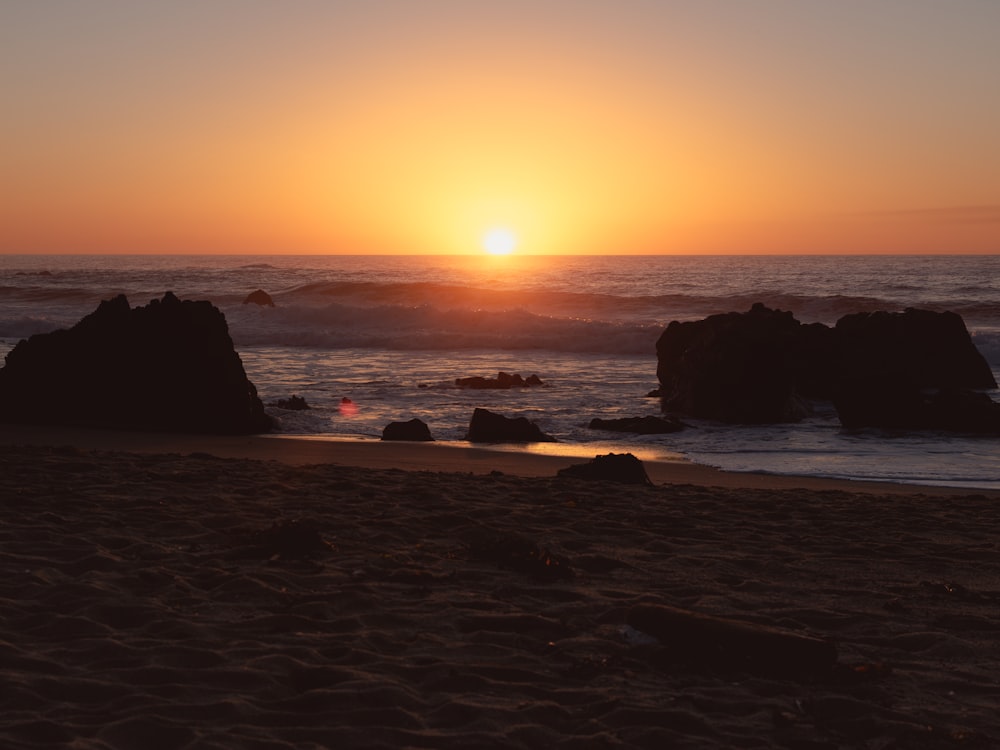 the sun is setting over the ocean on the beach