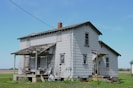 an old run down house sitting in the middle of a field