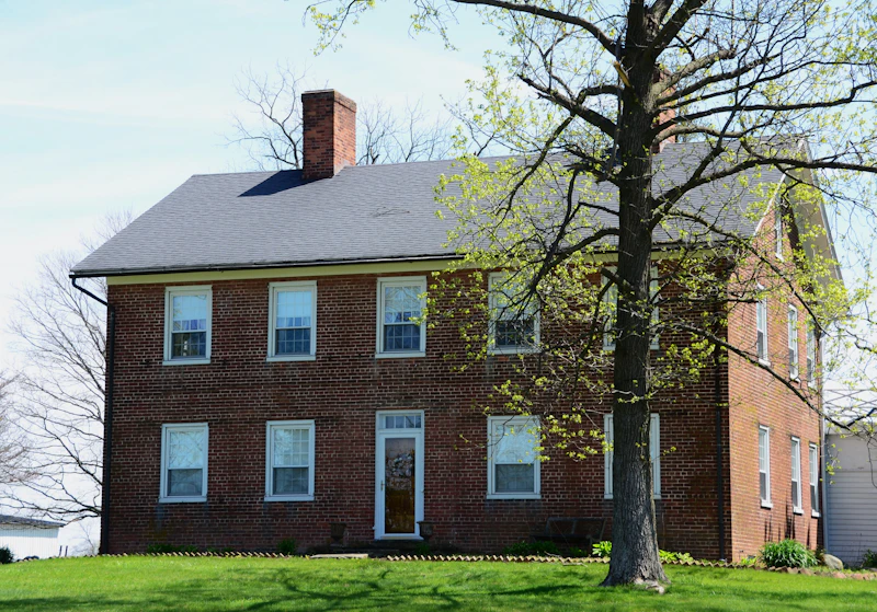 Large brick home with a mature shade tree in an established neighborhood
