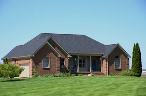 a brick house with a green lawn and a blue sky