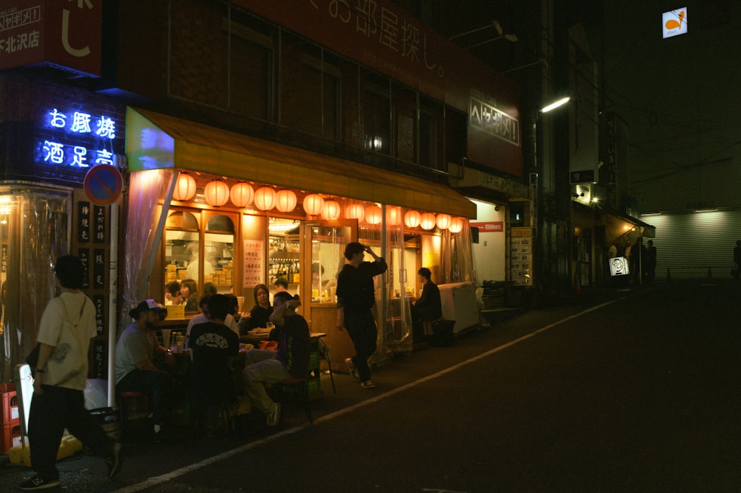 a group of people standing outside of a restaurant at night,