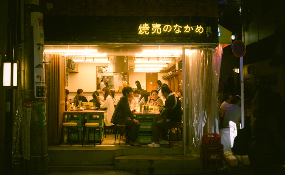 a group of people standing outside of a restaurant at night