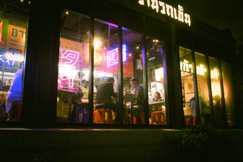 a group of people standing outside of a restaurant at night