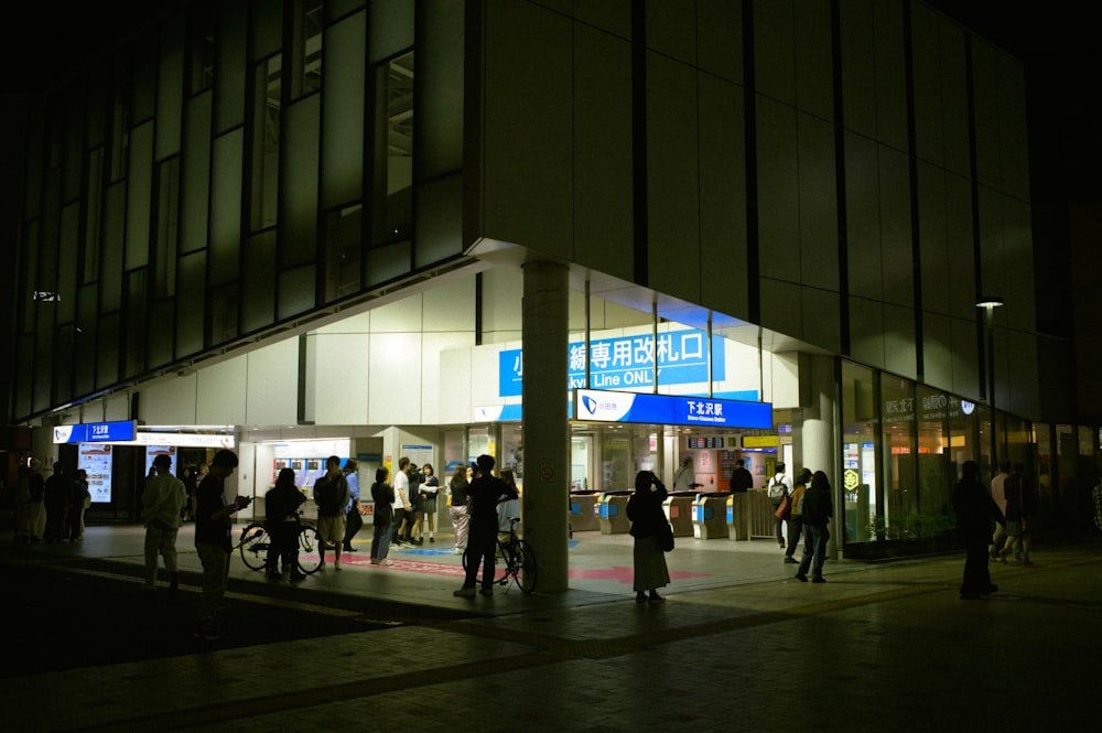 a group of people standing outside of a building at night