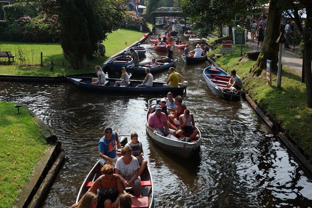 a group of people riding on top of boats down a river