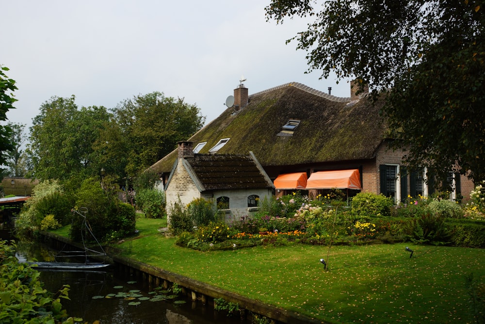 a house with a thatched roof next to a body of water
