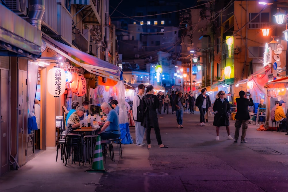 a group of people walking down a street at night