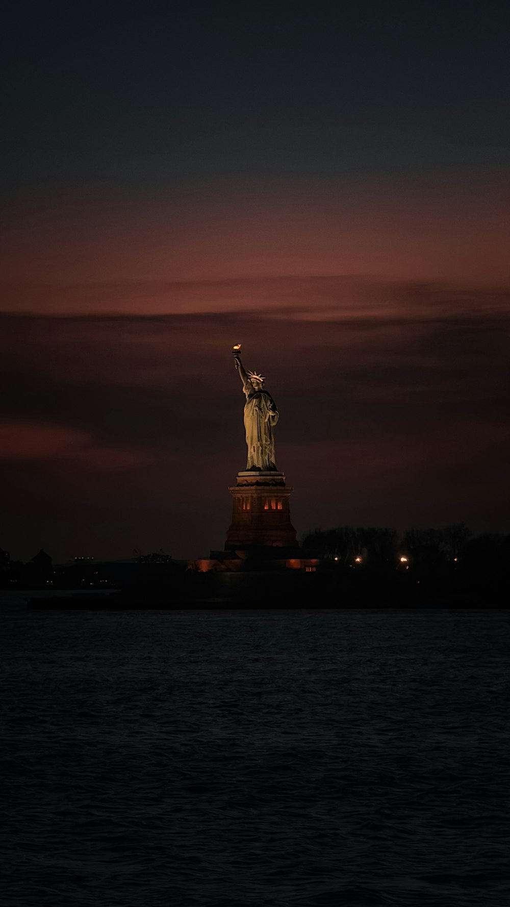 the statue of liberty is lit up at night