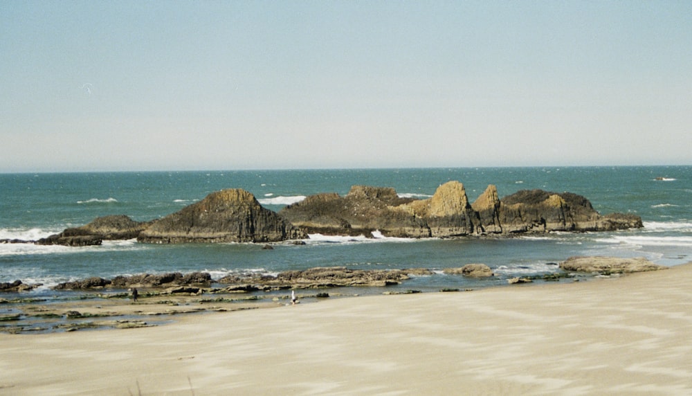 a group of rocks sitting on top of a sandy beach