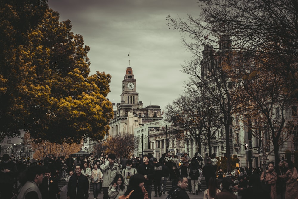 a crowd of people walking down a street next to tall buildings