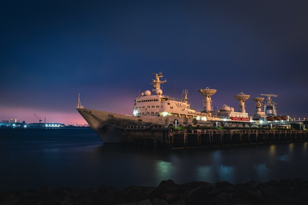 a large ship docked in a harbor at night