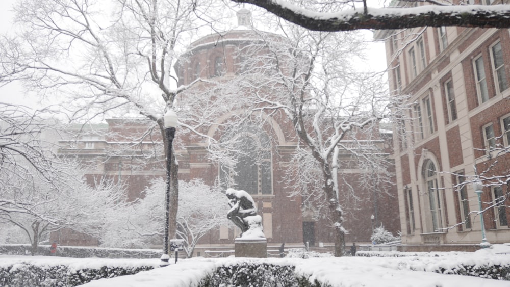 ein schneebedeckter Campus mit einer Statue im Vordergrund