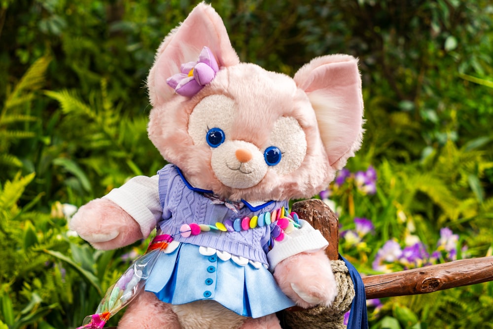 a pink teddy bear wearing a blue dress