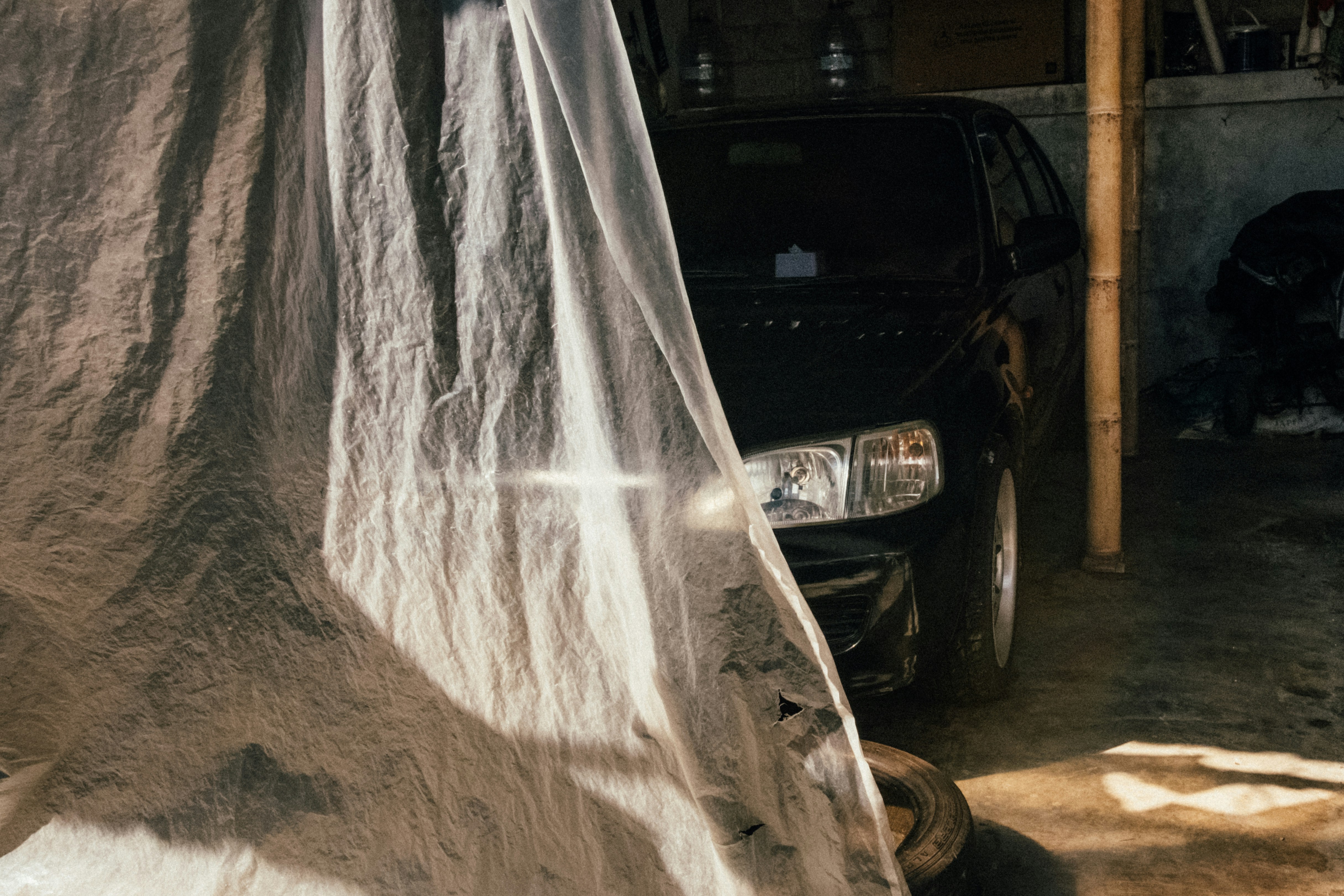 Ein mit einer weißen Plane verhülltes Auto in einer Garage