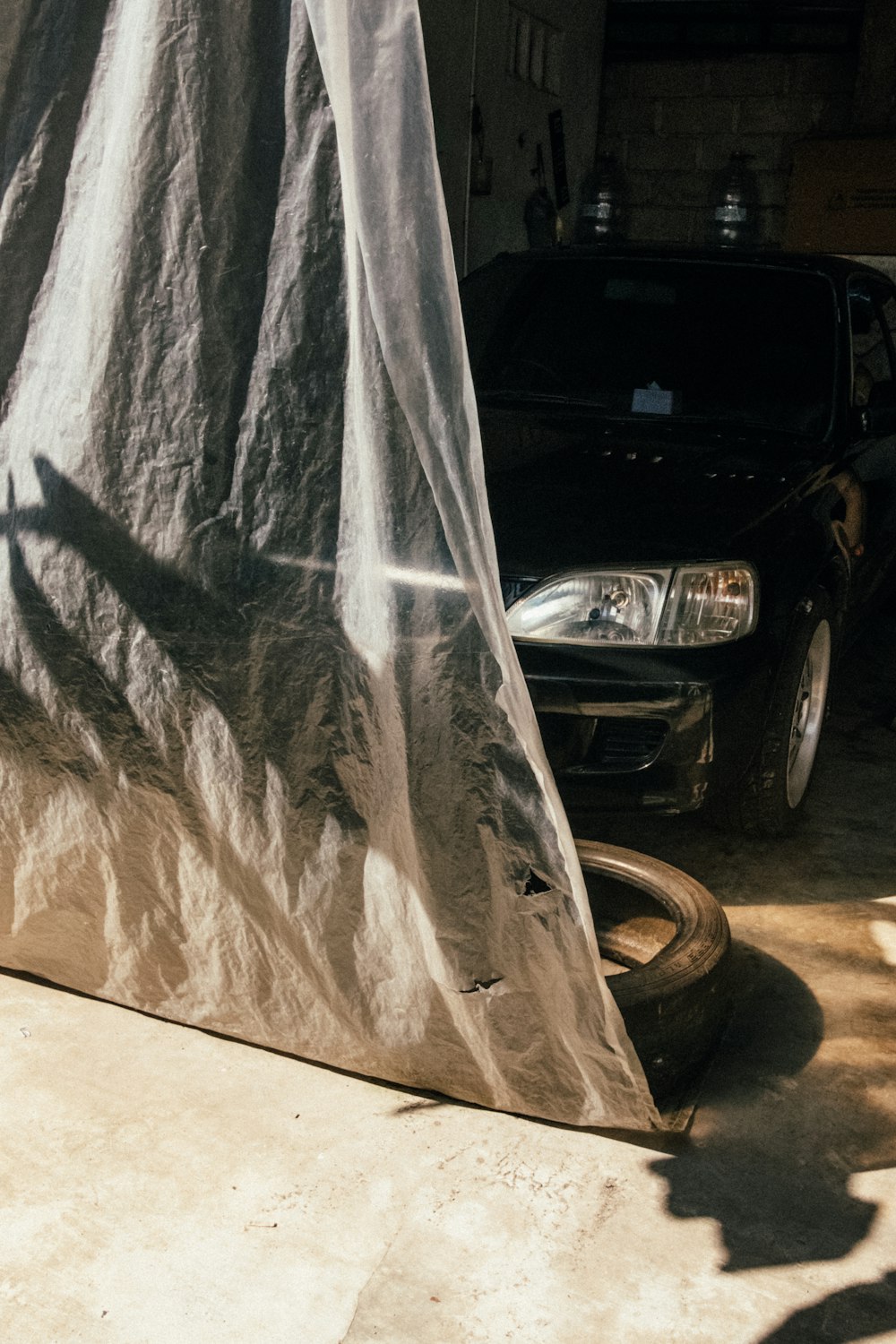 a black car parked in a garage under a tarp