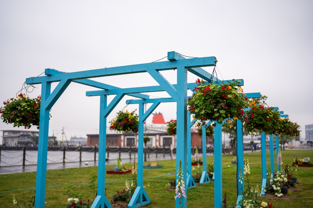 a row of blue wooden structures with flowers hanging from them