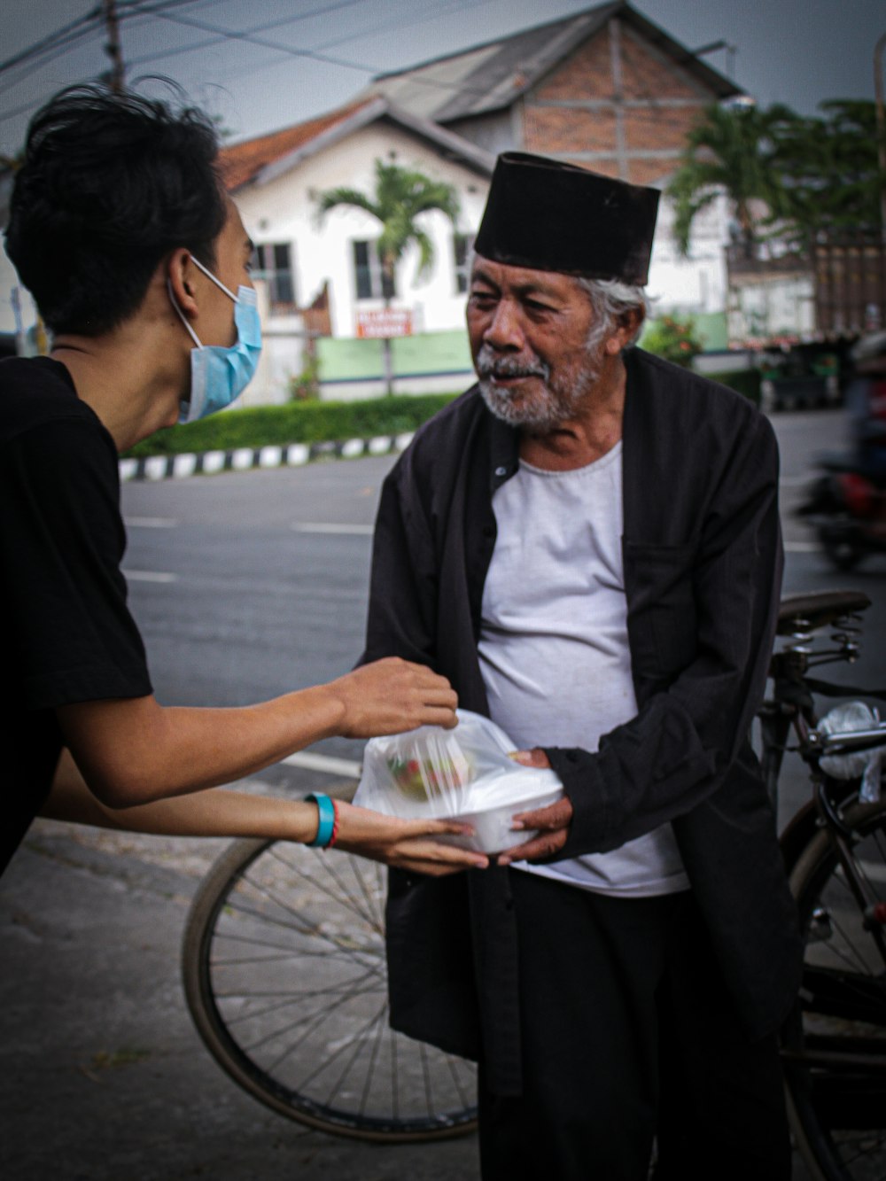 a man handing something to a woman on the street