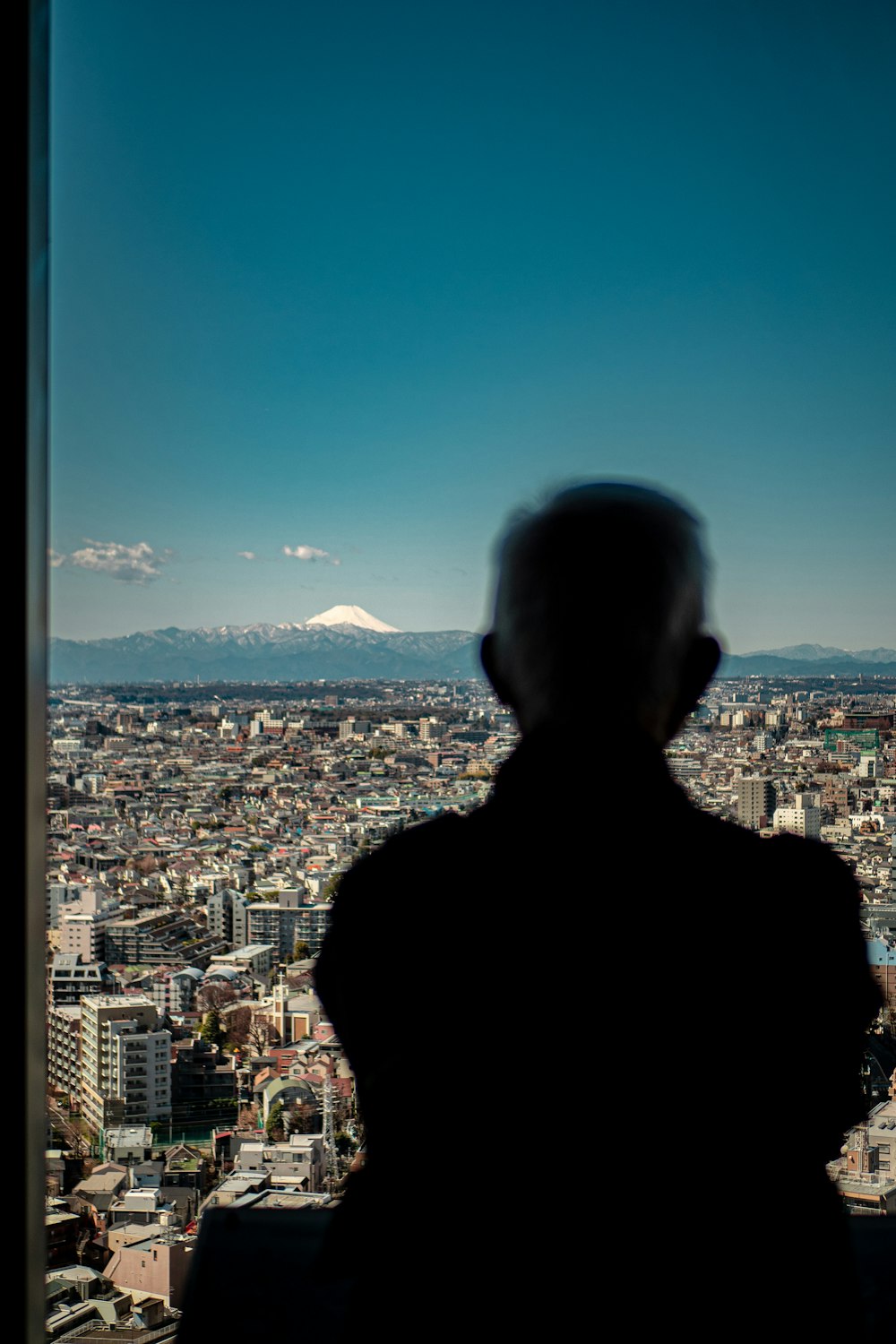 a man standing in front of a window overlooking a city