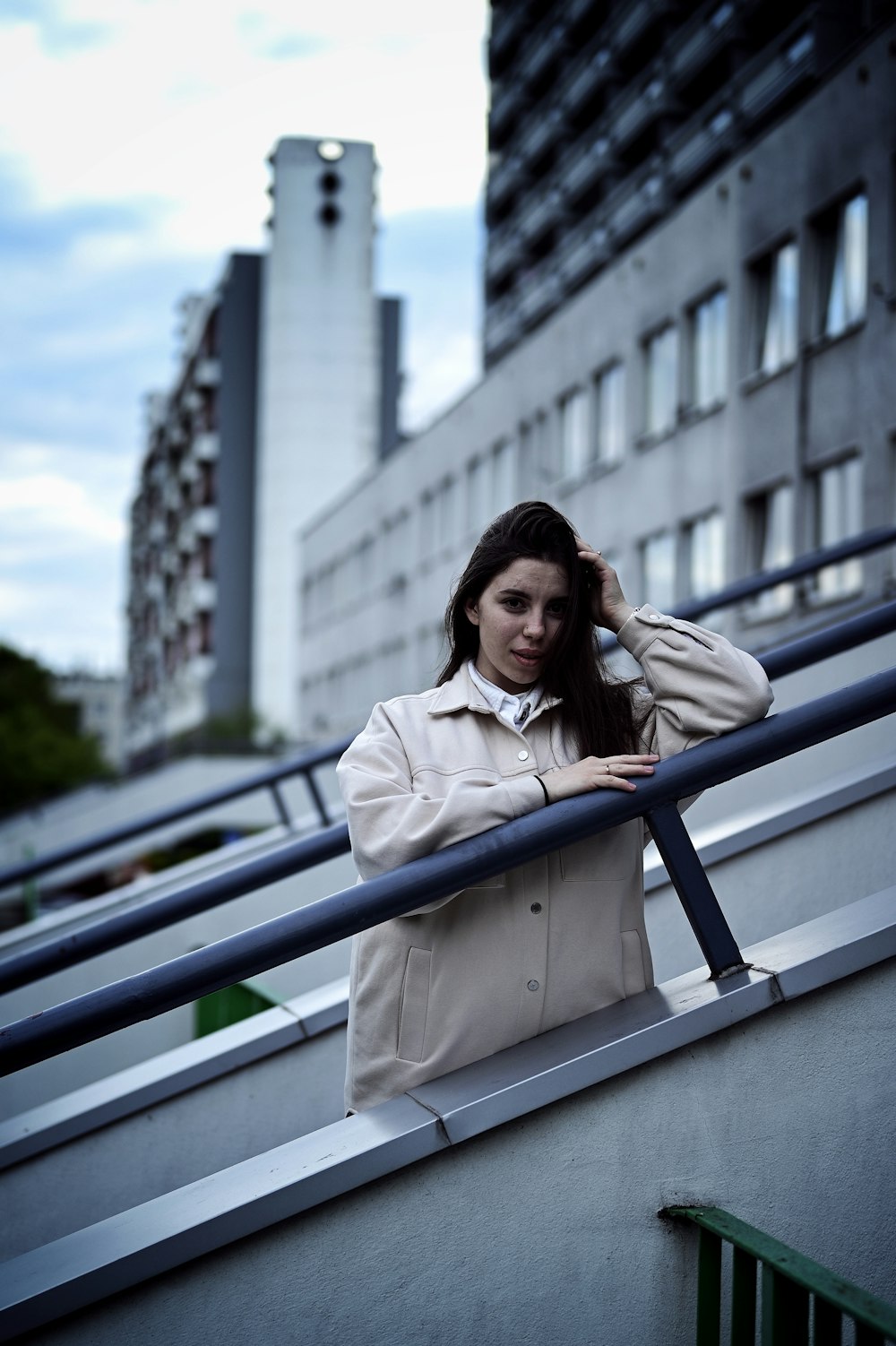 a woman in a trench coat leaning on a railing