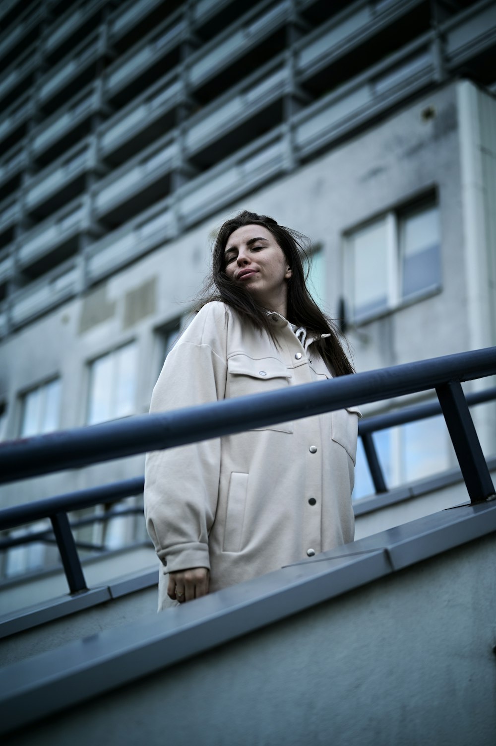 a woman standing on a balcony next to a building